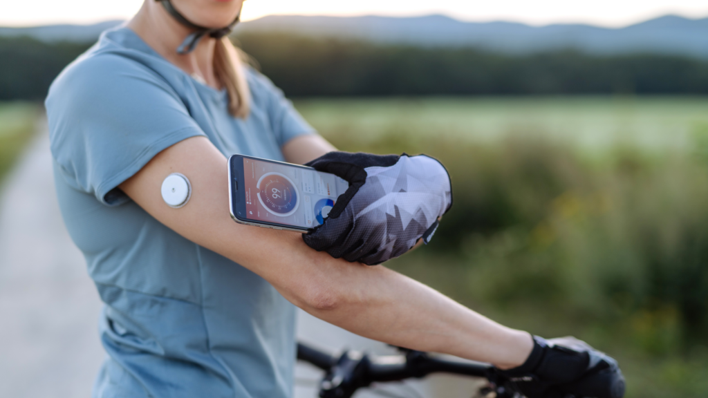 Man on bicycle checks blood glucose using continuous glucose monitoring device