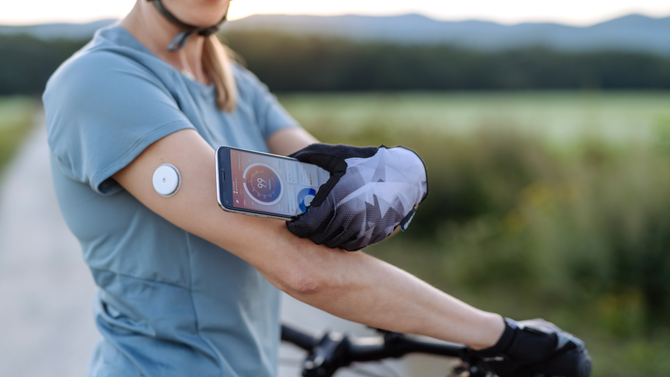 Man on bicycle checks blood glucose using continuous glucose monitoring device